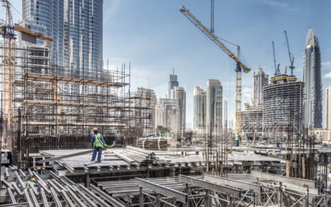 Laborers working on modern constraction site works in Dubai. Fast urban development consept